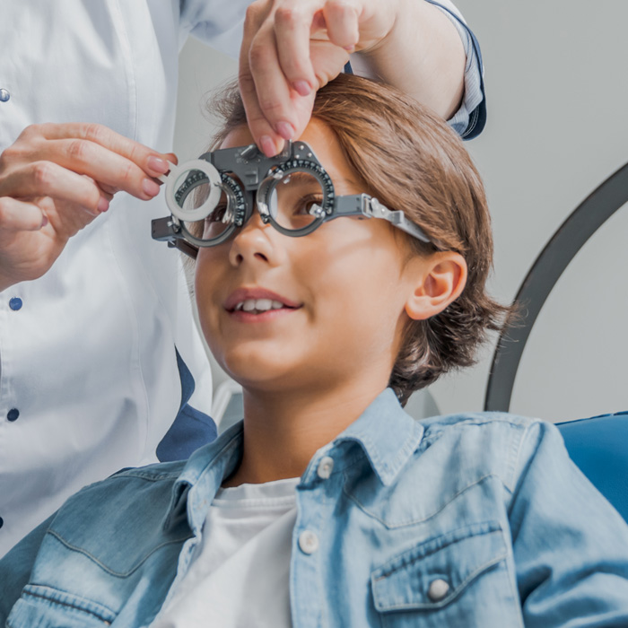 Especialista en óptica ajustando un foróptero a un niño durante un examen de la vista.